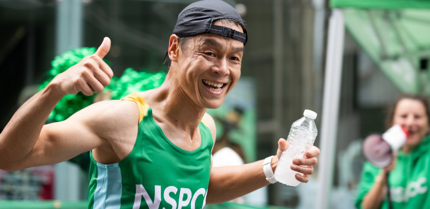 A man in an NSPCC vest running and smiling.