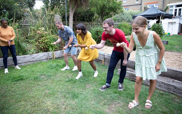 Some fundraisers laughing and smiling while taking part in an egg and spoon race.