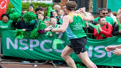Man in NSPCC vest running past a cheer point
