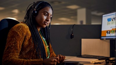 Childline counsellor sitting at a desk, wearing headphones and looking at computer