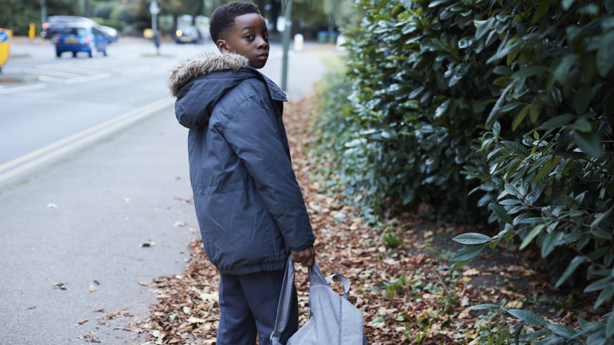 Young boy standing outside in street wearing coat