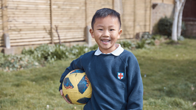 Boy holding a football in back garden