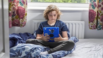 Young boy sat in his room using a tablet