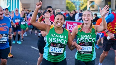Two Team NSPCC members running and smiling during the London Marathon.