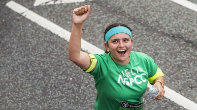 Woman in NSPCC vest running and cheering