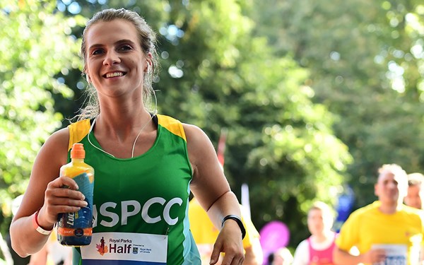 A Team NSPCC member running and smiling during the Royal Parks Half Marathon.