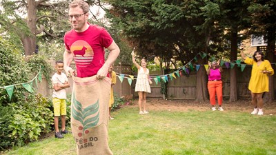 A group of people cheering on a sack race in a garden.