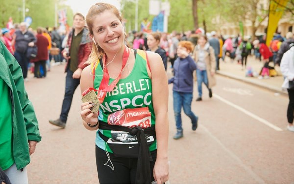 A woman holds a medal at the end of a marathon