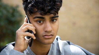 A teenager using their mobile while looking worried.